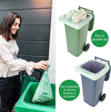 Charger l'image dans la galerie, Femme utilisant un sac poubelle compostable pour déchets bio, avec deux poubelles colorées en arrière-plan.