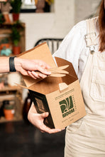 Charger l'image dans la galerie, Person holding a kraft box containing reusable sugarcane knives, showcasing eco-friendly product made in France.