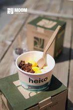 Charger l'image dans la galerie, Dessert in a cup with a wooden spoon next to eco-friendly packaging by Heiko on a wooden table.