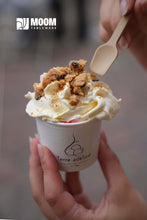 Charger l'image dans la galerie, Main holding a cup of ice cream topped with crumbs, using a biodegradable sugar cane spoon.