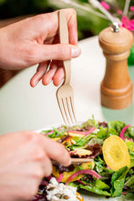 Charger l'image dans la galerie, Main hand holding a reusable 16cm fork, picking salad from a plate, with a wooden pepper grinder in background.