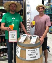 Charger l'image dans la galerie, Deux hommes présentant des pailles en verre locales, un portant un chapeau de paille, avec des boissons dans les mains.